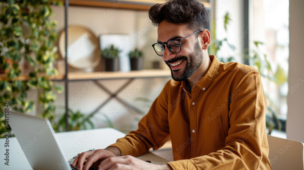 Aufkleber man smiling while working on a laptop in a modern office environment