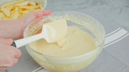 Chef mixing cake batter in a glass bowl. Apple cake preparation process