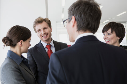 männliche und weibliche Kollegen stehen bei Meeting zusammen in grossen Loftbüro, München, Deutschland