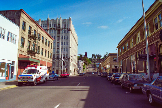 Astoria, Oregon, USA - May 12, 1992:  Grainy archival film photograph of Medix ambulance parked on Duane Street in historic downtown Astoria Oregon.  