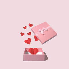 Heart shape paper out of gift box on pink background. Creative concept.