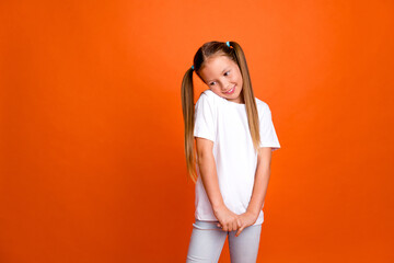 Portrait of adorable positive shy little girl empty space advert blank isolated on orange color background