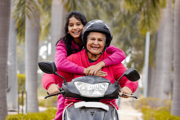 Indian Senior woman with Grand daughter Driving Scooter moped Enjoying Life ,Insurance Concept - obrazy, fototapety, plakaty