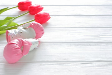 Tulips flowers and boxing gloves on wooden background, femenism concept