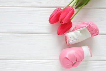Tulips flowers and boxing gloves on wooden background, femenism concept