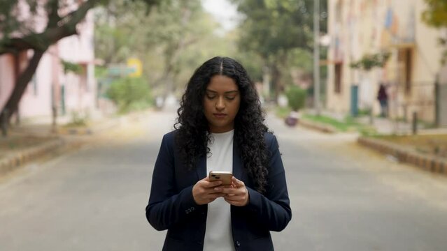 Serious Curly Hair Indian Businesswoman Texting While Walking
