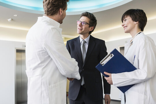 Colleagues at a pharmaceutical company meeting with a client in the foyer. Munich, Bavaria, Germany