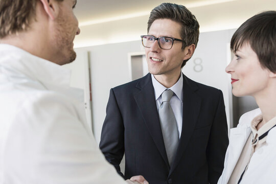 Colleagues at a pharmaceutical company meeting with a client in the foyer. Munich, Bavaria, Germany