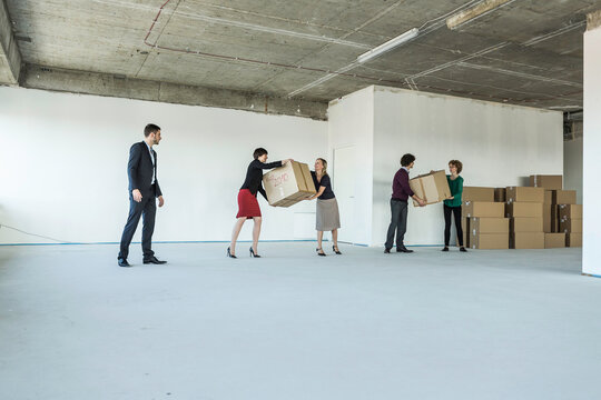 Colleagues of a startup helping each other move in, passing boxes to each other. Munich, Bavaria, Germany