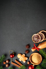 Gingerbread cookies, spices and Christmas decorations at black. Top view with space for text.