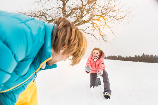 Young beautiful woman having a snow ball fight with her boyfriend. Wolfratshausen, Bavaria, Germany 