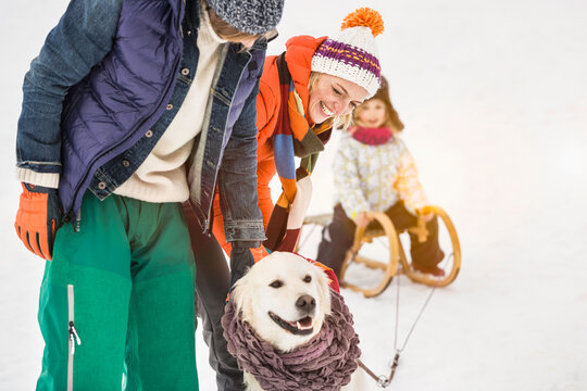 Parents and young girl sledding and playing in a snowy landscape in winter. Wolfratshausen, Germany