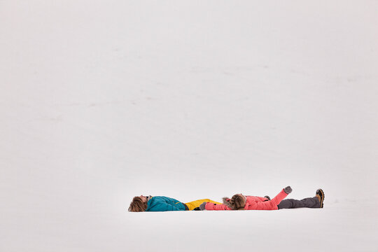 Coupel making snow angels in the snow in winter. Wolfratshausen, Bavaria, Germany