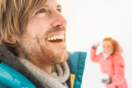 Young couple having a snow ball fight and playing in a snowy landscape in winter. Wolfratshausen, Germany