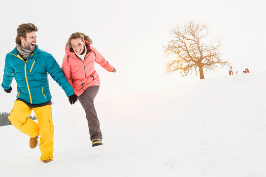 Young couple having a snow ball fight and playing in a snowy landscape in winter. Wolfratshausen, Germany
