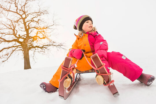 Young girl sledding and playing in a snowy landscape in winter. Wolfratshausen, Germany