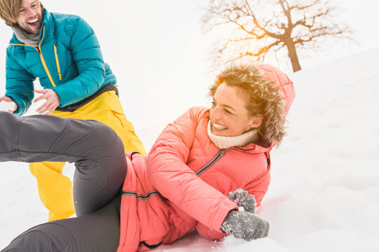 Young couple having a snow ball fight and playing in a snowy landscape in winter. Wolfratshausen, Germany