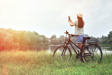 Woman walking with bicycle using mobile phone in park or field. ECO friendly transport concept....