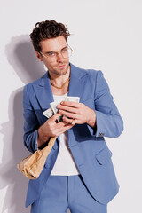 Trendy man in suit and tank top holding cash and paper bag on grey, fashion concept 
