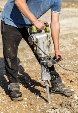Close-up of a construction site with a drilling rig and pneumatic equipment. A large hammer drill in the hands of a builder