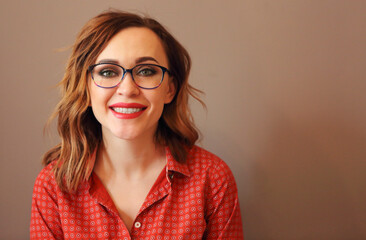 Portrait of attractive brunette woman with eyeglasses wearing red blouse