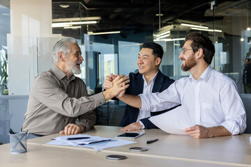Three smiling male professionals celebrate a successful partnership in a bright, contemporary...