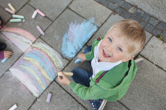 kid painting with street chalk on the pavement