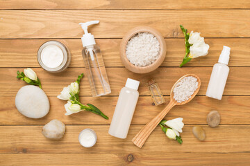 Flat lay with spa products and flowers on wooden background
