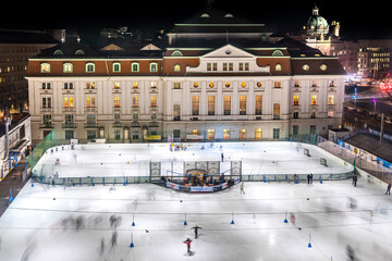 Illuminated ice skating rink in Vienna, Wien, Austria in middle of the historic city center. With...
