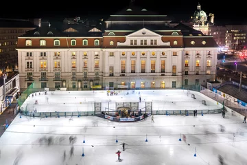 Zelfklevend Fotobehang Illuminated ice skating rink in Vienna, Wien, Austria in middle of the historic city center. With many people skating and playing ice hockey in front of palace. © Thomas