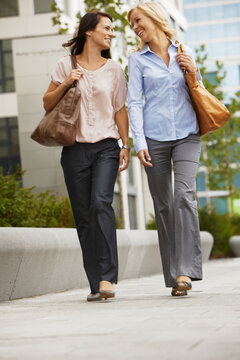 two young business women walking in front of an office building