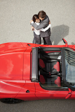 Top shot of couple in business attire standing next to electric sports car. Munich, Bavaria, Germany