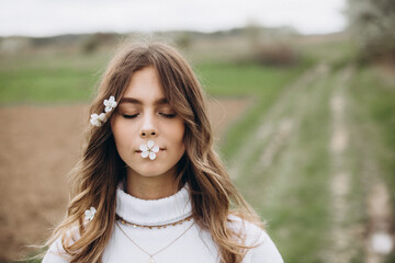 
portrait of a young girl with long hair and flowers on her head on the street. spring portrait. Awakening female beauty