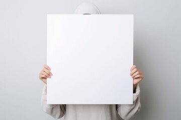 A girl holds a blank white poster and covers her face with it. Generative AI