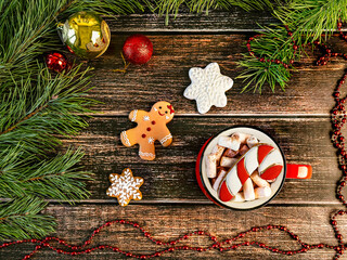 Red cup with marshmallow and gingerbread lollipop, top view. Christmas composition with gingerbread cookies on a wooden background