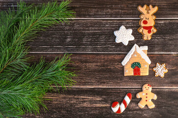 Christmas gingerbread, deer, gingerbread man, house, lollipop, snowflakes, pine branches on dark wooden background. Winter Christmas background with gingerbread.