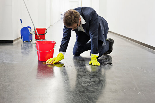 Man dressed in a suit cleaning hall way in an office. Munich, Bavaria, Germany