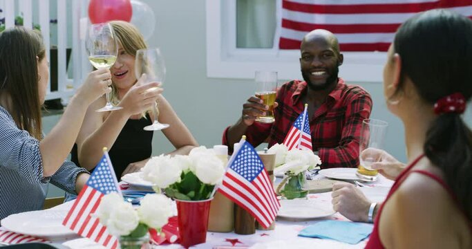 Friends, alcohol and toast at party, American flag and celebration for Independence Day with drinks and bbq outdoor. Diversity, beer and wine on fourth of July, holiday and people with cheers in USA