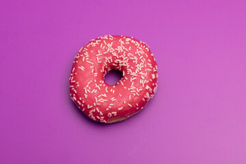 close up of pink donut against plain purple backdrop