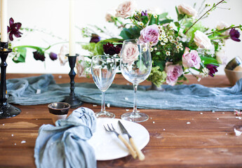 Bouquet of pink flowers on a table set for dinner with candles