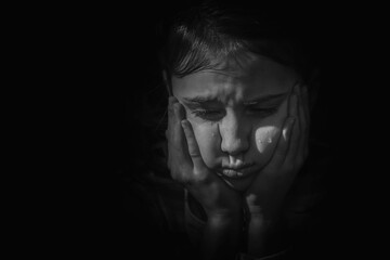 Cute little sad offended child girl is crying on a black background.  Copy space.