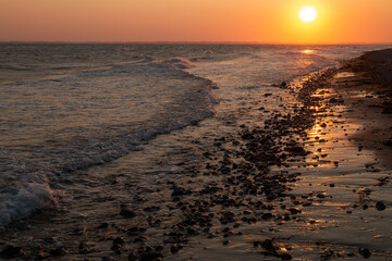 Traumhafter Sonnenuntergang an der Ostsee mit Wellen im Abendrot.