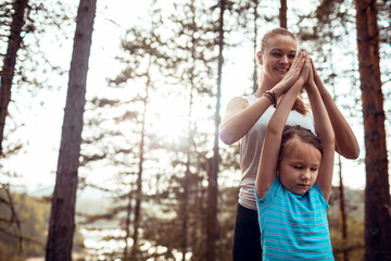 Loving mother and daughter doing yoga in nature