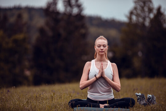 Young woman meditating on a grass field in nature
