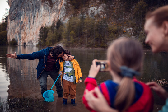 Happy young family taking picture while fishing in lake