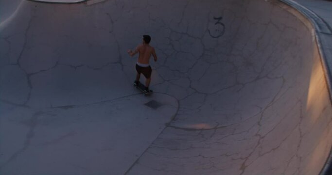 Young skater rides with flow inside a pool during a warm summer sunset. Subculture and freedom of skateboarding. Free spirit lifestyle. Authentic sport concept.