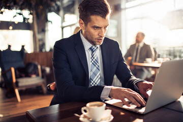 Focused businessman using laptop in cafe