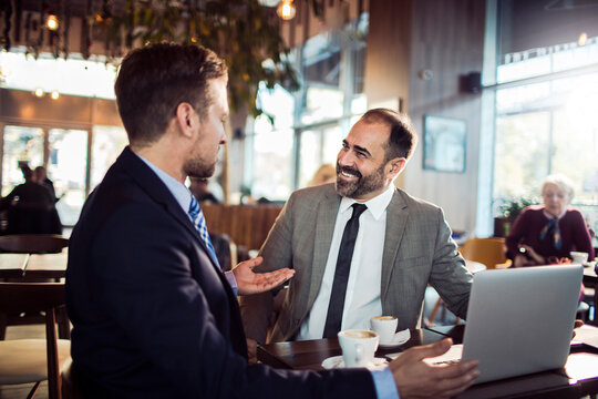 Two young businessmen drinking coffee in cafe