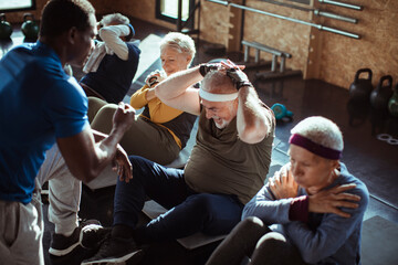 Diverse senior people working out with trainer in gym