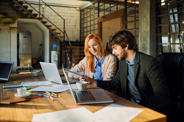 Young man and woman discussing document in office